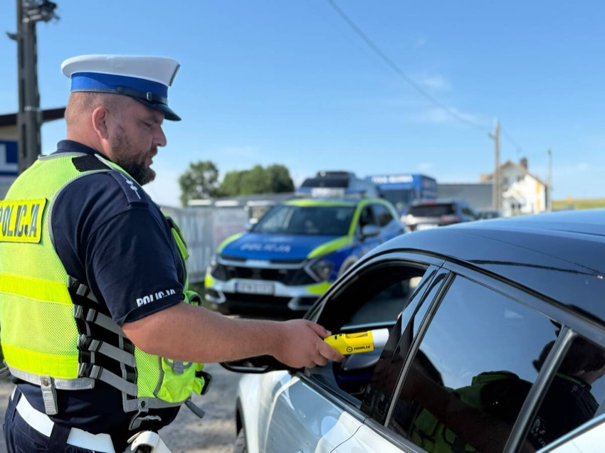 Policjant bada trzeźwość kierowcy przy zatrzymanym samochodzie
