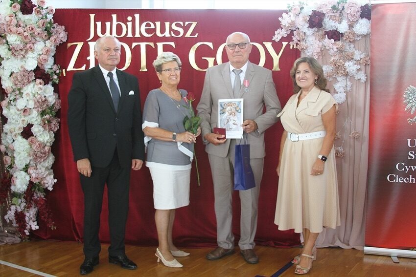 Para jubilatów z medalem w towarzystwie senator i burmistrza przed ścianką z napisem Jubileusz Złote Gody w Ciechanowcu
