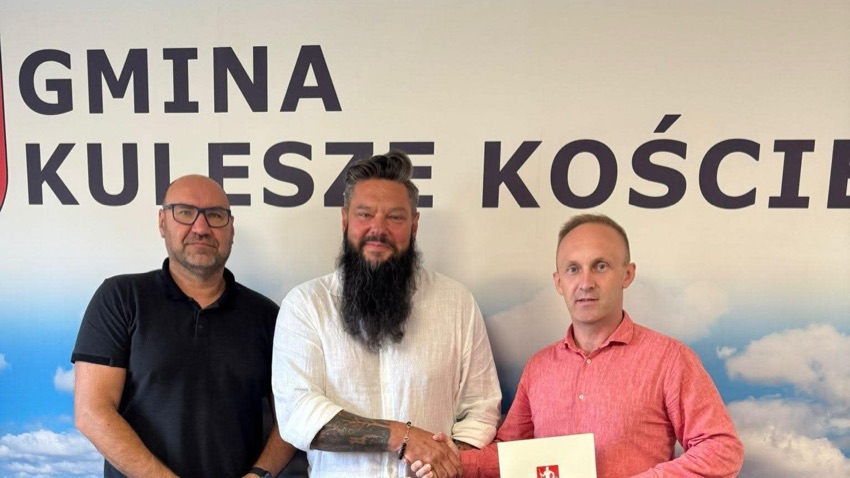 Trzej mężczyźni z podpisanymi umowami przed ścianką z napisem Gmina Kulesze Kościelne