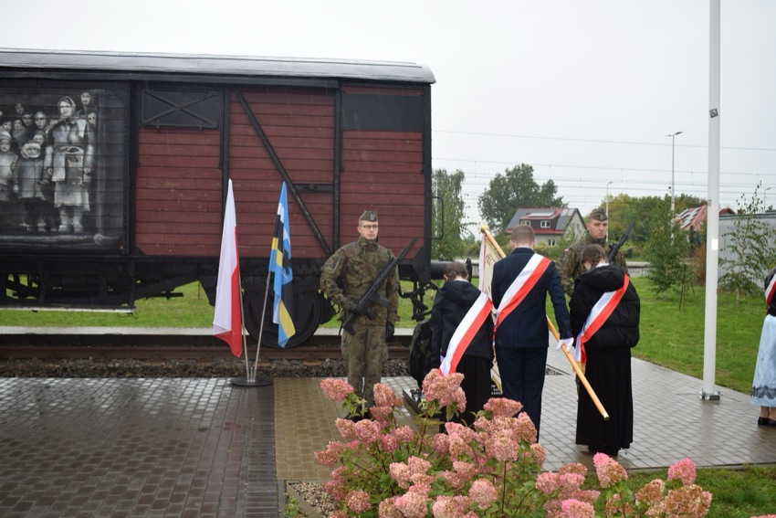 Wagon-pomnik na torach w Szepietowie, przy nim warta honorowa żołnierzy i poczty sztandarowe podczas obchodów Dnia Sybiraka