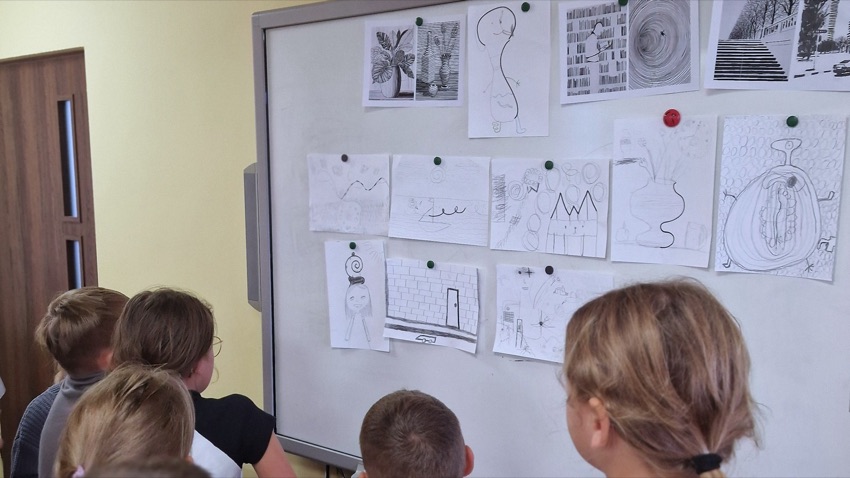Rysunki dzieci przypięte do tablicy w pracowni plastycznej w Nowych Piekutach