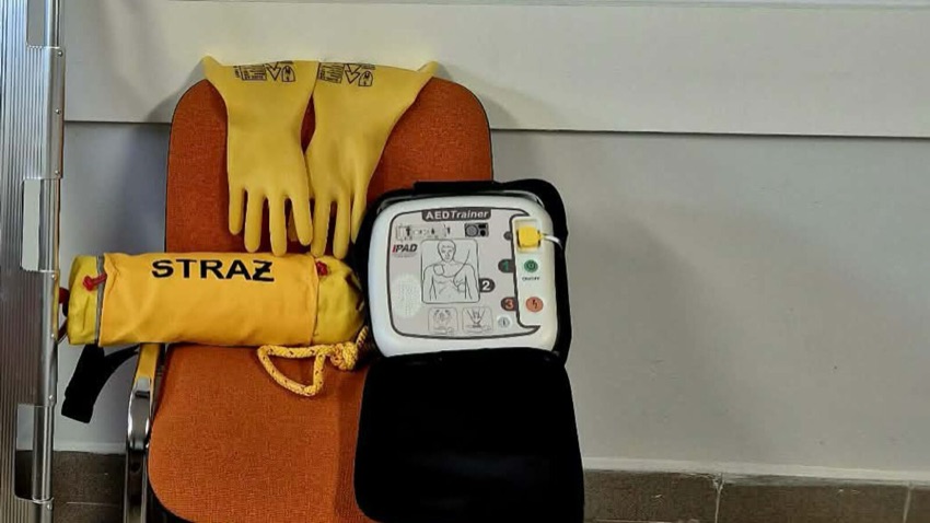 Rękawice dielektryczne, rzutka ratownicza i defibrylator treningowy na krześle w remizie w Kuleszach Kościelnych