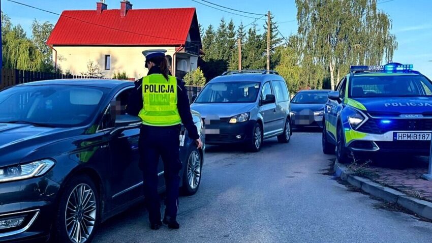 Policjantka podczas kontroli drogowej, za nią radiowóz i zatrzymane samochody