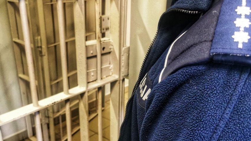Policjant przy kracie celi w policyjnym areszcie