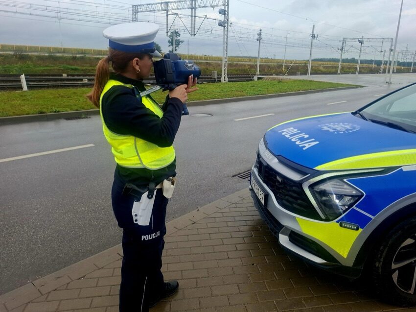 Policjantka drogówki mierzy prędkość pojazdów ręcznym miernikiem