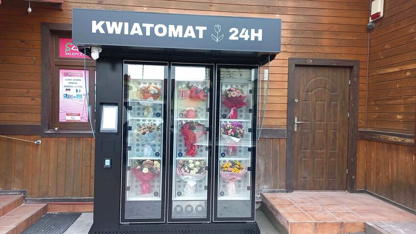 Kwiatomat 24h w Ciechanowcu przy drewnianym budynku