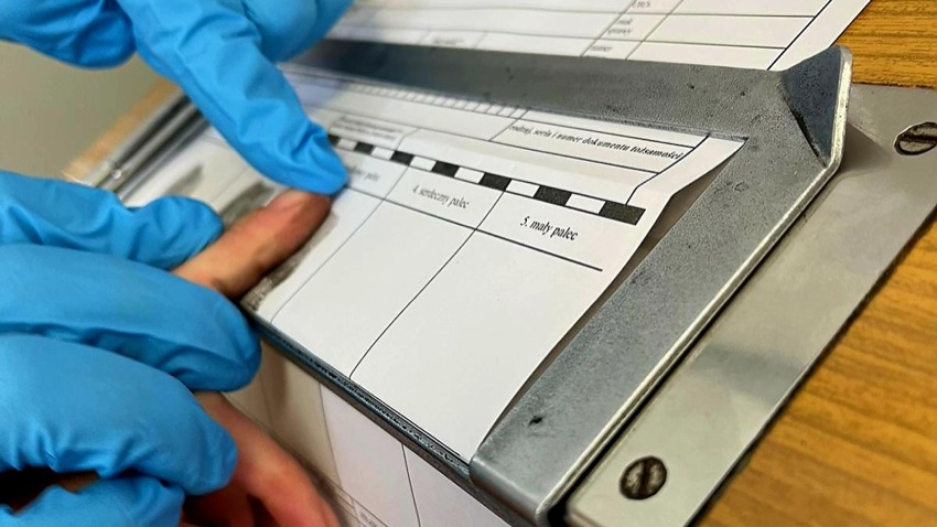 Policjant w rękawiczkach pobiera odciski palców - zdjęcie poglądowe