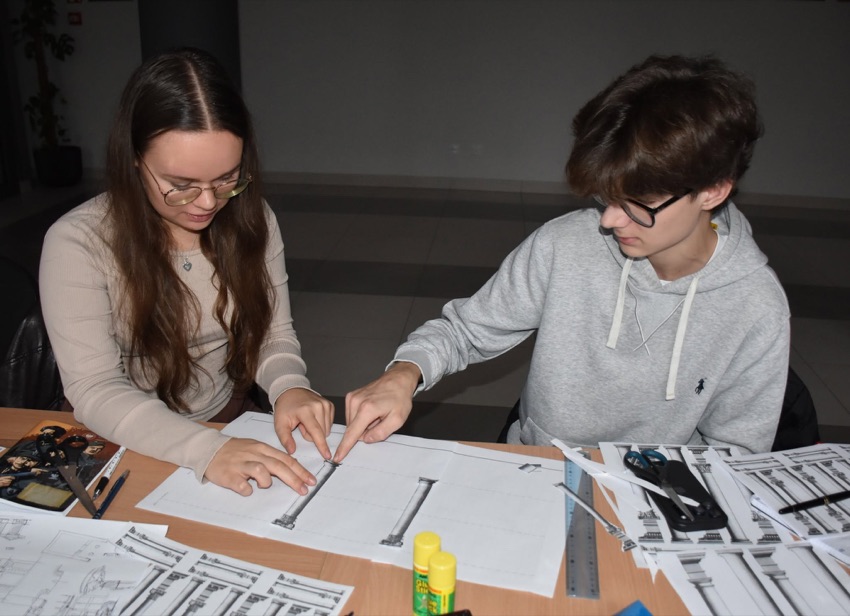 Uczestnicy projektu RETROTOPIA przy rysunkach architektonicznych w bibliotece w Wysokiem Mazowieckiem